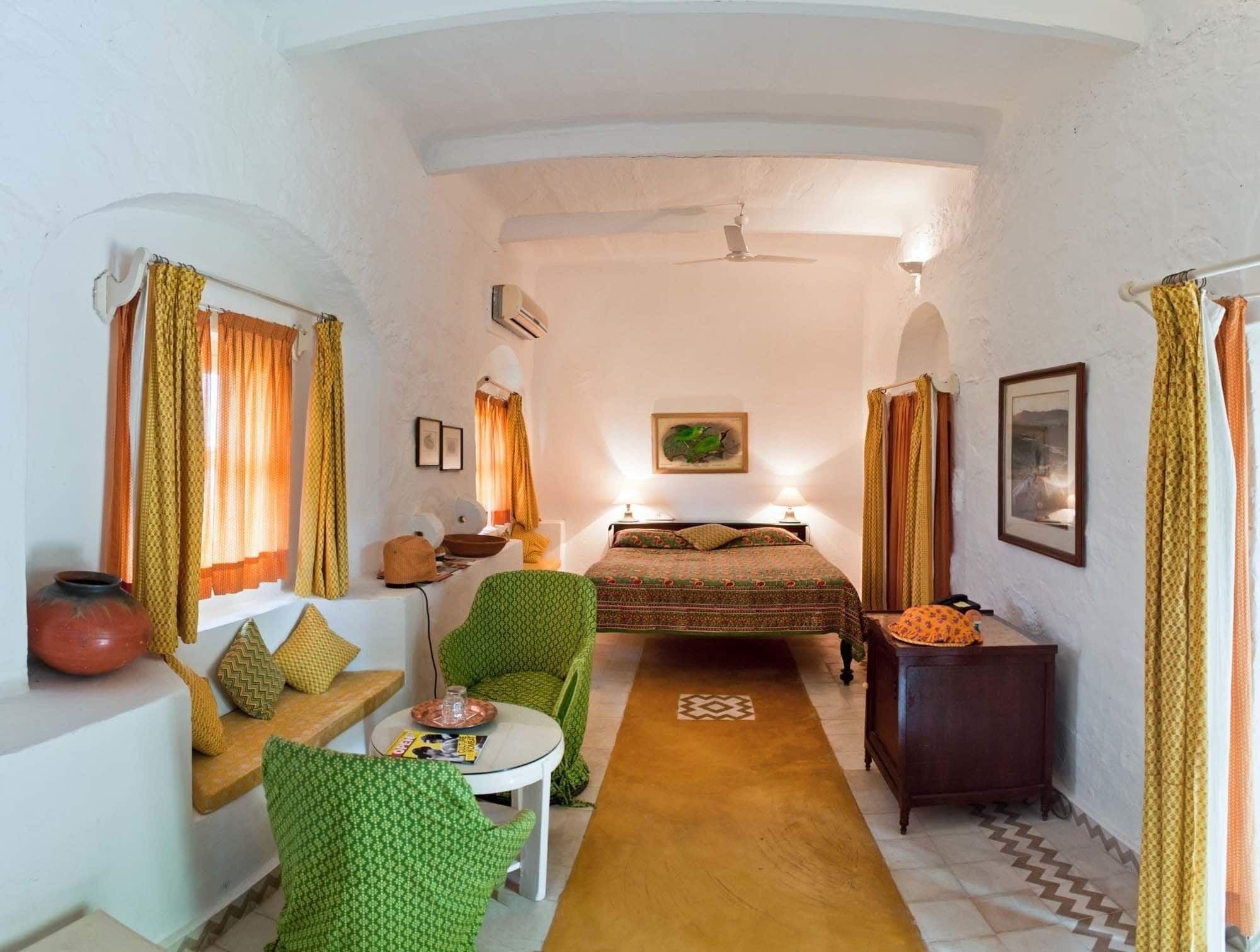 A compact room with a bed, a small table, a chair, and a sofa.