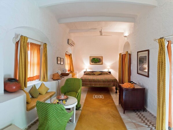 A compact room with a bed, a small table, a chair, and a sofa.