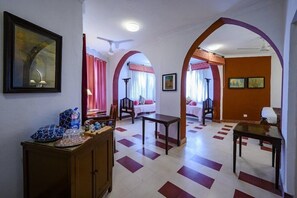 Habitació d'hotel amb un paviment a quadradets, zona de menjador i saló amb sofà i taula.