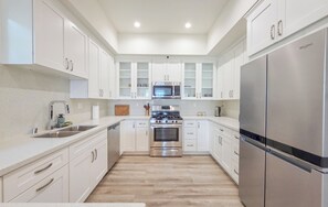 A modern kitchen with white cabinetry, stainless steel appliances, and a central island.