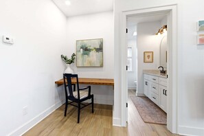 Ein modernes Interieur mit einem Holztisch, einem Stuhl, einer weißen Vase mit Pflanze und einem Bild an der Wand.