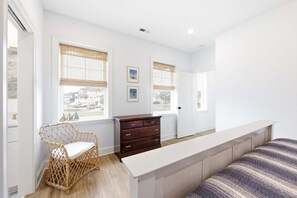 A bedroom with a bed, a dresser, a chair, and two windows with blinds. - Reelin 22: Canalfront, Boat Dock, Pirate's Cove Community Amenities (Manteo)