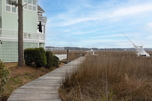 A coastal building with a wooden deck leading to a beach area. - Reelin 22: Canalfront, Boat Dock, Pirate's Cove Community Amenities (Manteo)