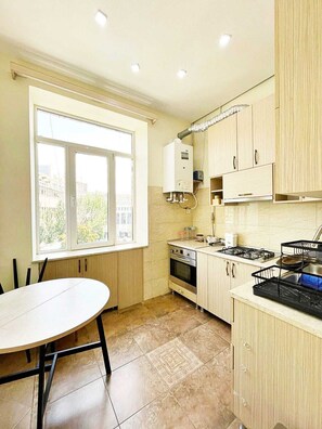 A kitchen with a dining table, a stove, and a window. - Bright & Cozy Yerevan Apartment with City View Near City Center & Self Check-in (Yerevan)