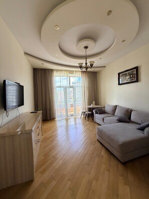 Una sala moderna con televisor de pantalla plana, un sofá, un mueble de madera y un comedor con mesa y sillas.
