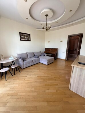 A living room with a grey sectional sofa, a wooden coffee table, and a dining table with chairs. - Bright & Cozy Yerevan Apartment with City View Near City Center & Self Check-in (Yerevan)