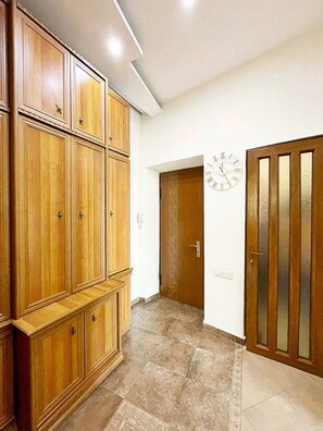 Un corridoio con armadietti in legno, una porta con pannello di vetro e un orologio a parete.