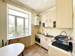 A compact kitchen with a window, a stove, and a sink. - Bright & Cozy Yerevan Apartment with City View Near City Center & Self Check-in (Yerevan)