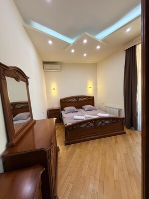 A bedroom with a wooden bed, a nightstand, a dresser, and a mirror. - Bright & Cozy Yerevan Apartment with City View Near City Center & Self Check-in (Yerevan)