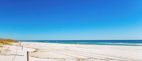 A beach with a clear sky, sandy shore, and a fence.