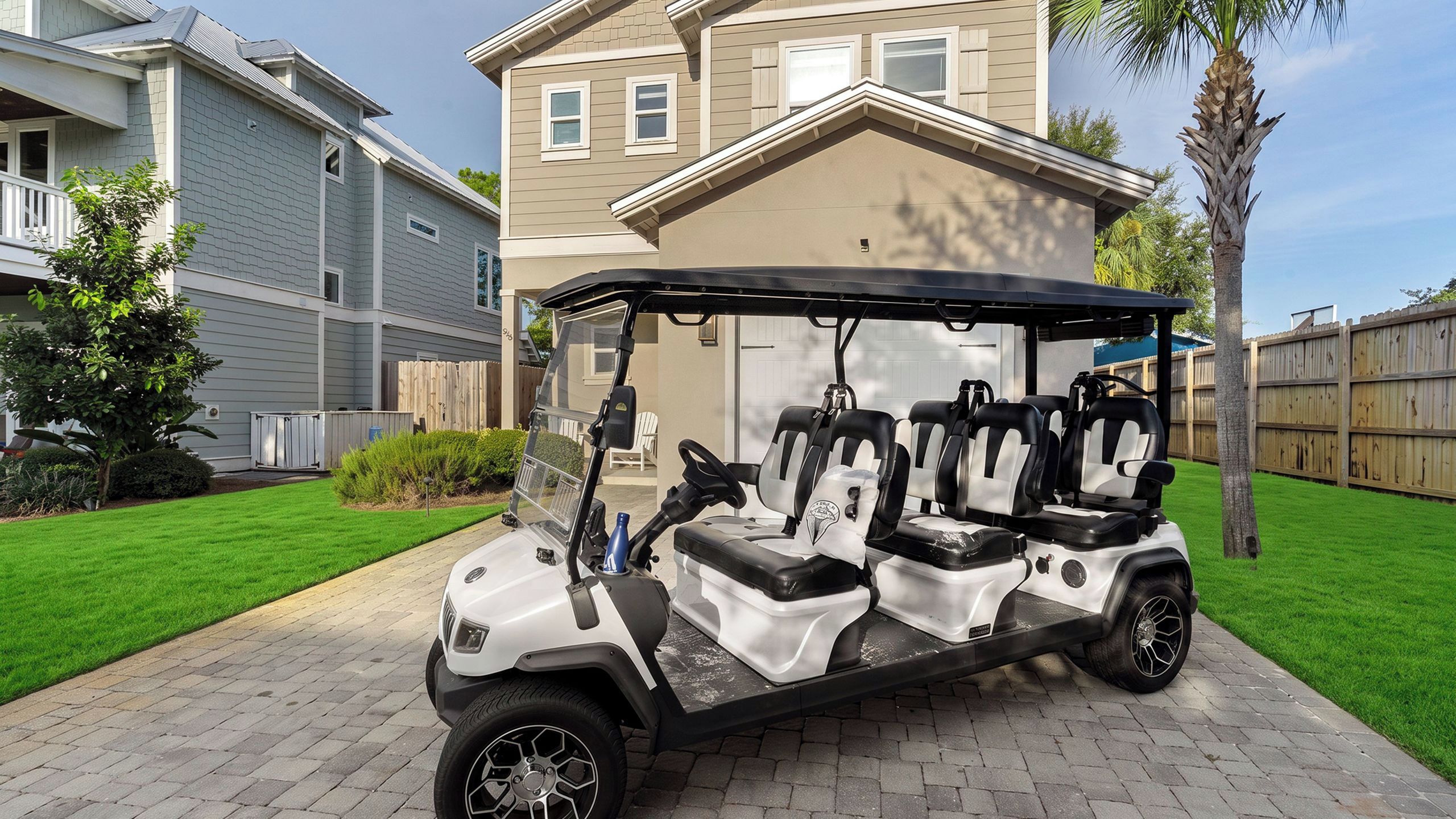 A golf cart parked on a paved driveway with a house in the background.