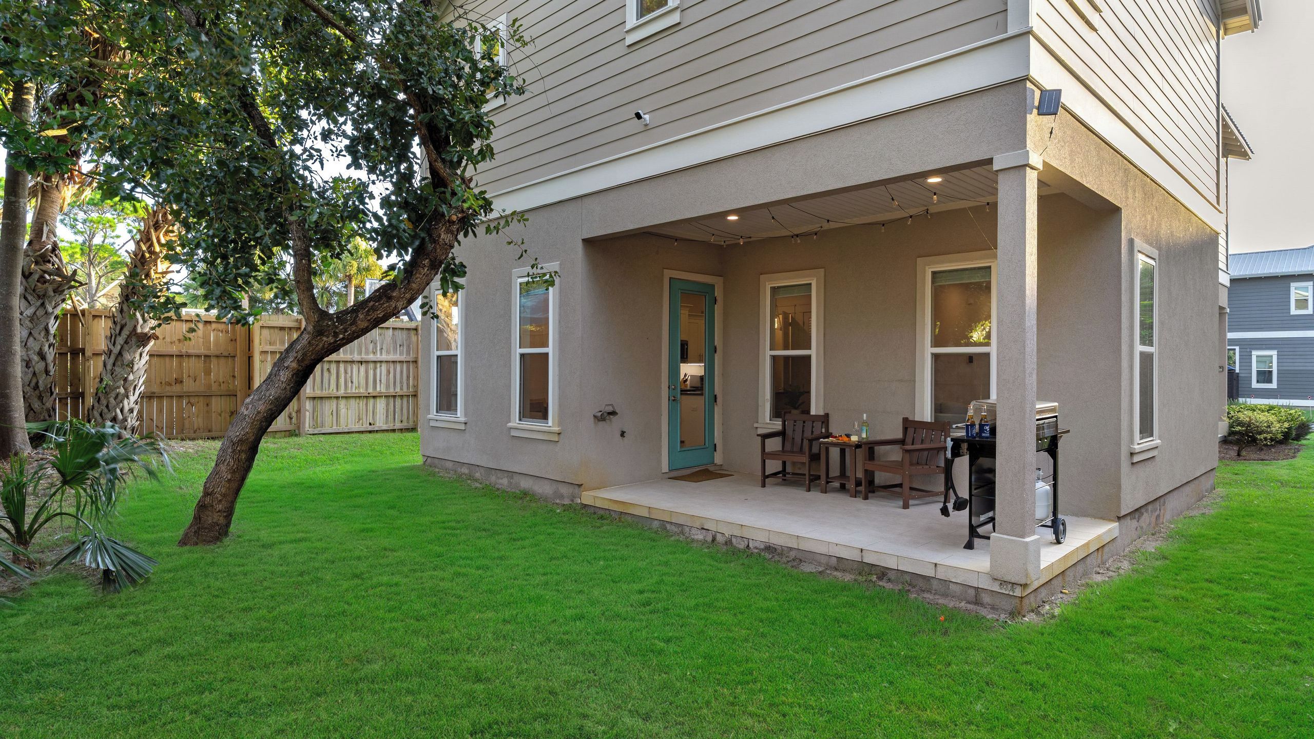 A house with a covered patio, a dining area with a table and chairs, and a barbecue grill.