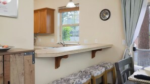A kitchen with wooden cabinets, a built-in bench, a window, and a wall clock. - Hollygrape Pedal & Pine Hideaway by Avantstay Bend Hideaway Deck + Near Mt. Bachelor + Breweries (Bend)