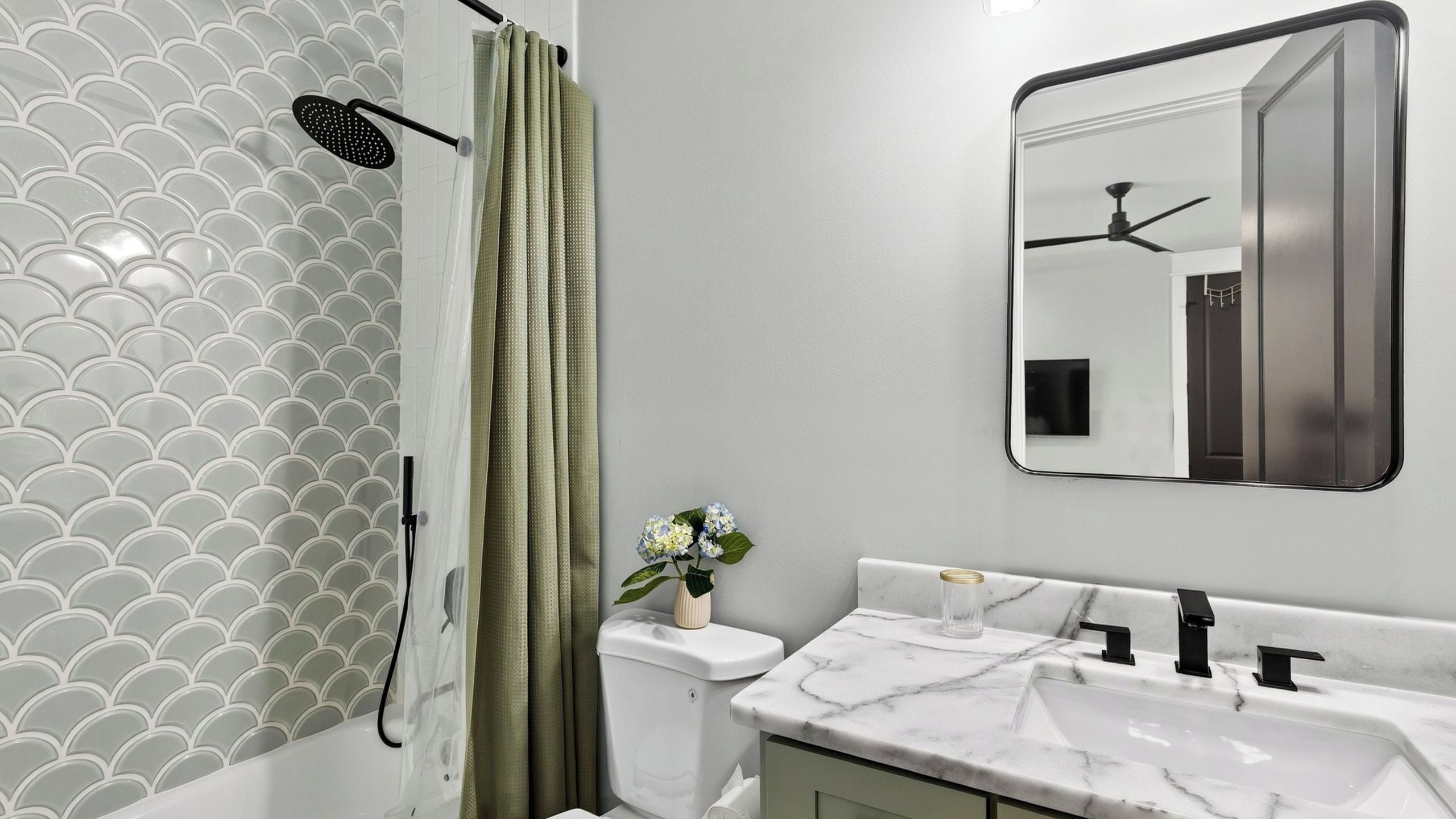 A bathroom with a shower, toilet, sink, and mirror.