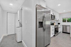 Una cocina moderna con electrodomésticos de acero inoxidable, armarios blancos y un ventanal que proporciona luz natural.