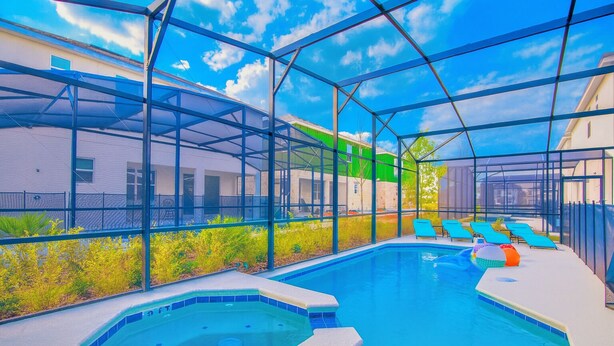 Una piscina con hidromasaje, rodeada por una estructura de cristal y sillones de relax azules.