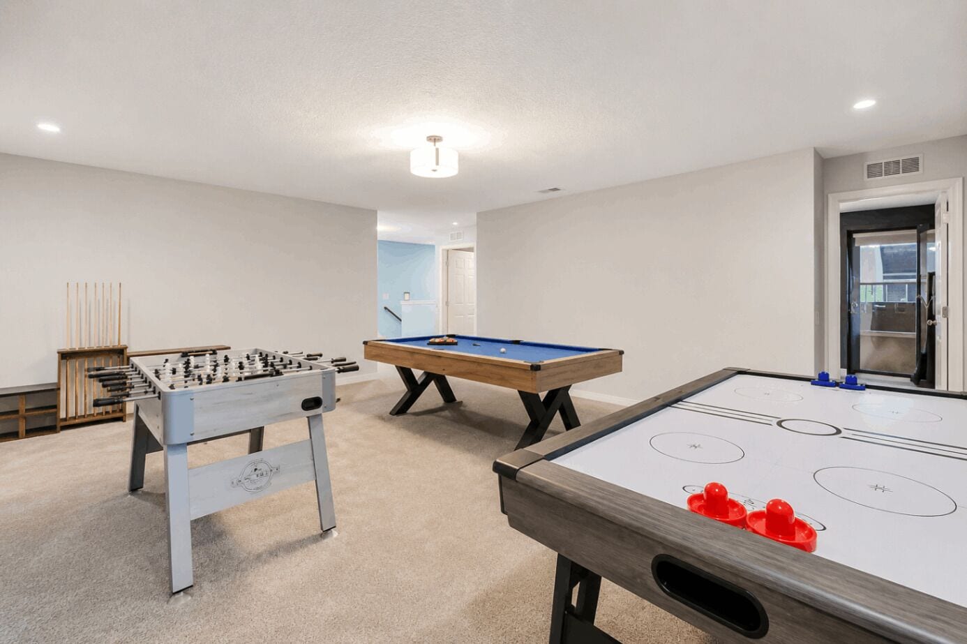 Una habitación con mesa de fútbol de mesa, mesa de billar y mesa de shuffleboard.