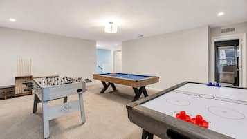 Una habitación con mesa de fútbol de mesa, mesa de billar y mesa de shuffleboard.