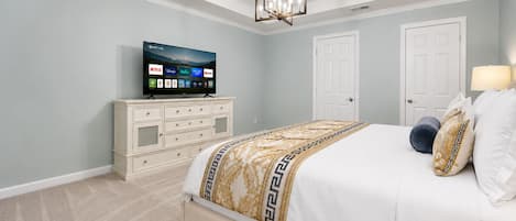 Une chambre à coucher avec un lit, un téléviseur posé sur une commode et un ventilateur de plafond.