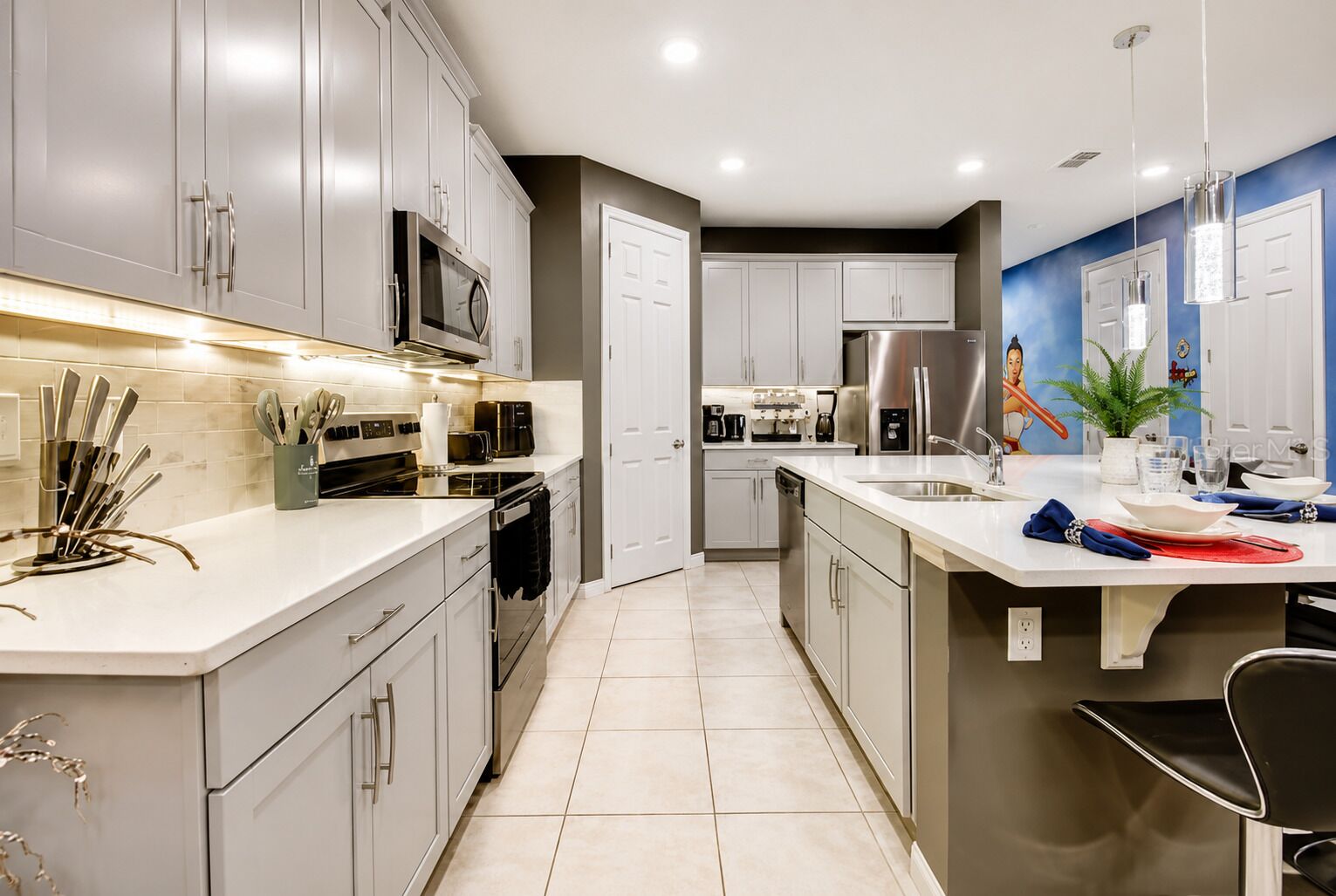 A modern kitchen with stainless steel appliances, white cabinetry, and a central island with seating.