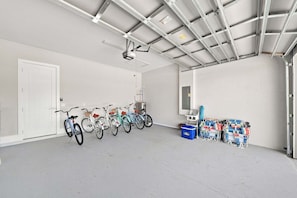 A spacious indoor area with a row of bicycles, a ceiling fan, and storage bins. - New! Dream Chaser • New Luxury Build • Heated Saltwater Pool/Spa • 1 Mile to Vanderbilt Beach! (Naples)