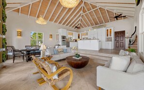A spacious living area with a high ceiling, a dining set, and a kitchen in the background. - 3 King Suites | Pool + Mahogany Run | Magens Bay (St. Thomas)