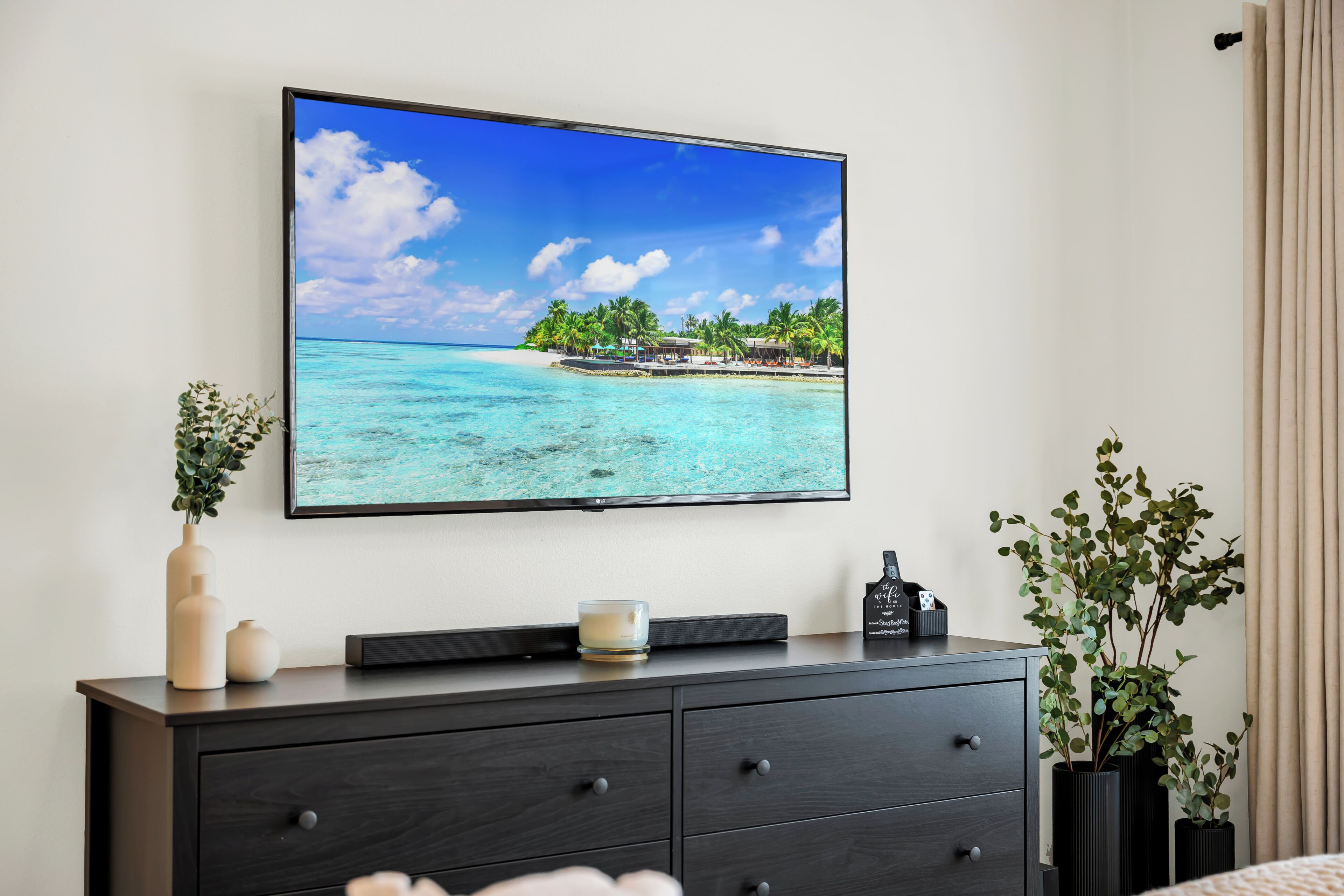 A television mounted on a wall displaying a tropical beach scene.