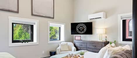 Une chambre à coucher comprenant un lit, une chaise, une commode et un climatiseur fixé au mur.