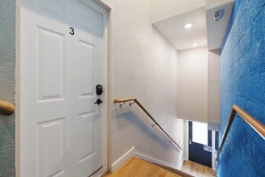 A staircase with a handrail, a white door with a number, and a blue wall. - Three Downtown Apartments | large groups | private | laundry (Traverse City)