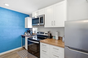 A modern kitchen with white cabinets, a stainless steel refrigerator, a microwave, and a dishwasher. - Three Downtown Apartments | large groups | private | laundry (Traverse City)