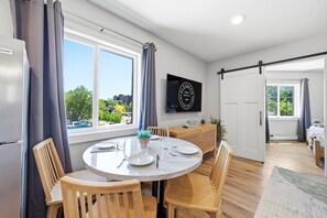 A dining area with a round table, chairs, and a view of the outside. - Three Downtown Apartments | large groups | private | laundry (Traverse City)