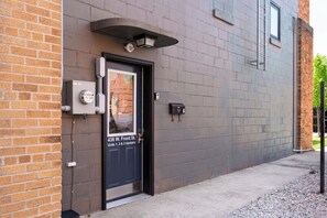 A building entrance with a black door, a utility meter, and a sign indicating '436 W. Front St. Units 1, 2 & 3 Upstairs.' - Three Downtown Apartments | large groups | private | laundry (Traverse City)