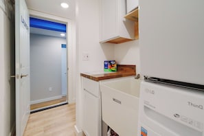 A laundry area with a white dryer, a wooden countertop, and a blue door leading to another room. - Three Downtown Apartments | large groups | private | laundry (Traverse City)