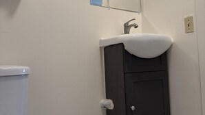 Un baño con inodoro, lavamanos y espejo, y un mueble bajo.