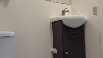 A bathroom with a toilet, a sink with a mirror above it, and a cabinet below.