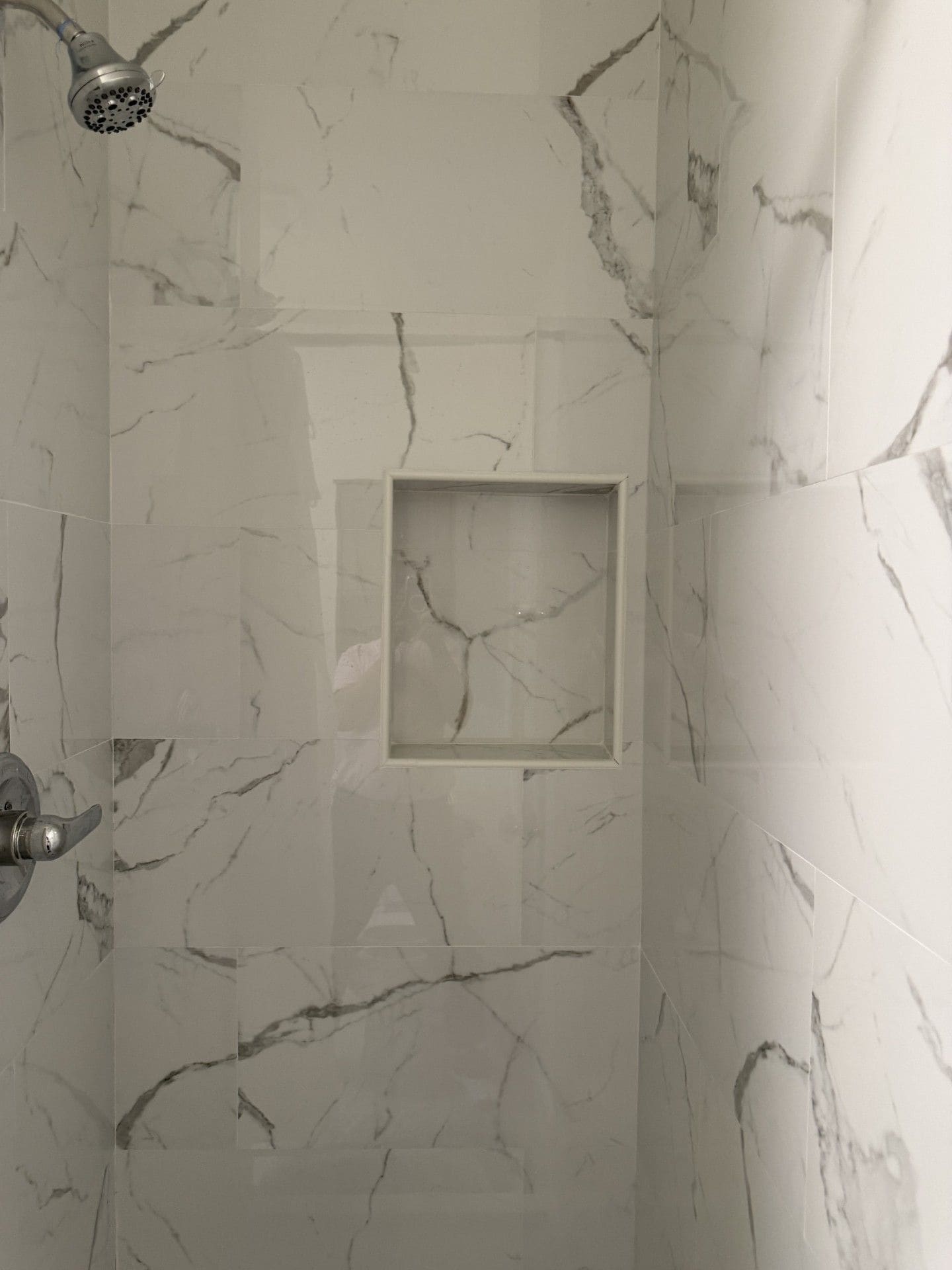A bathroom with marble walls and a shower area.