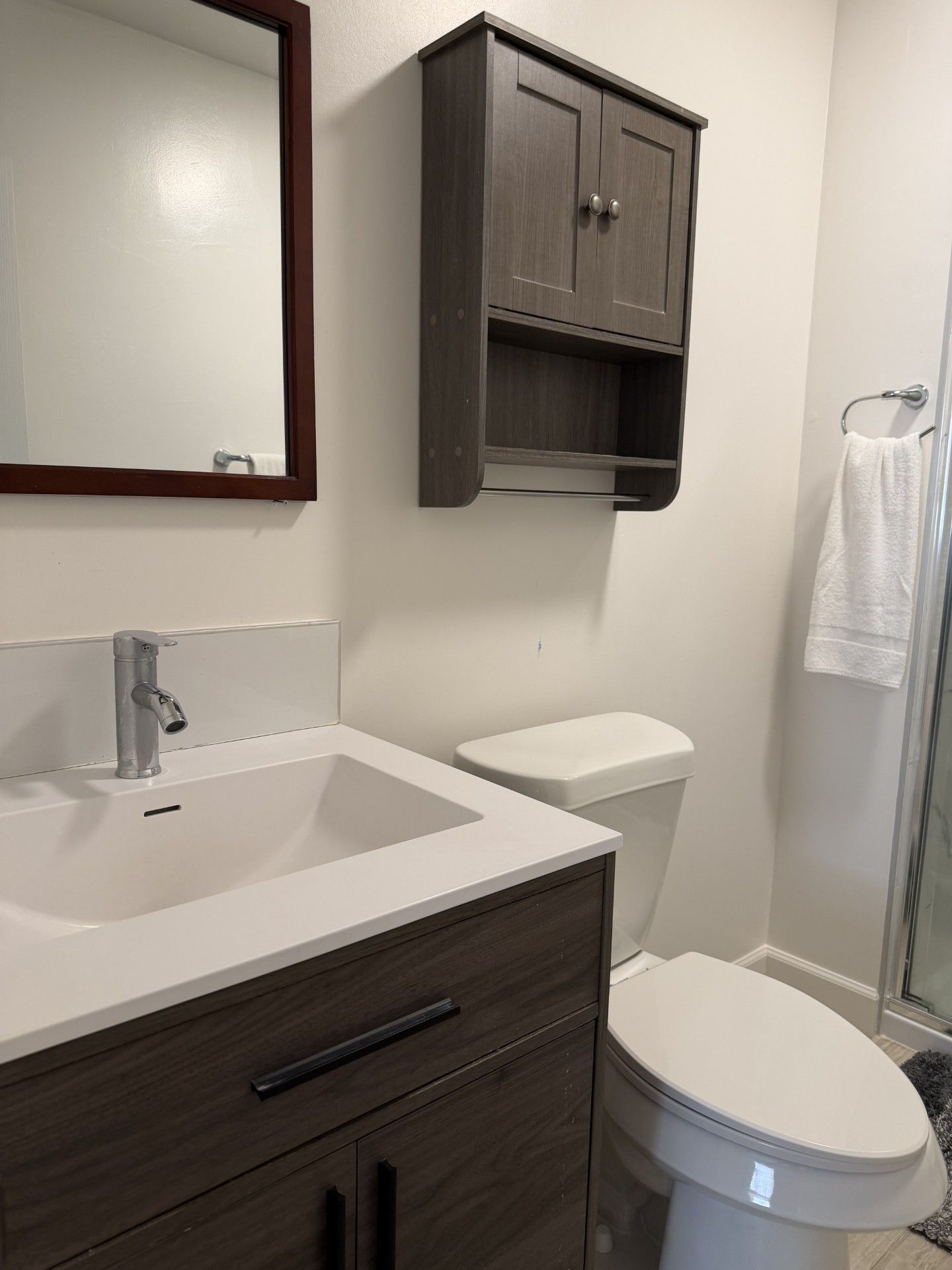 A bathroom with a white sink, dark wooden cabinet, and a toilet.