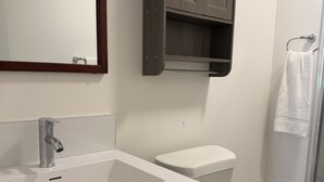 Un baño con un lavamanos blanco, un mueble de madera oscura y un inodoro.