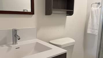A bathroom with a white sink, dark wooden cabinet, and a toilet.