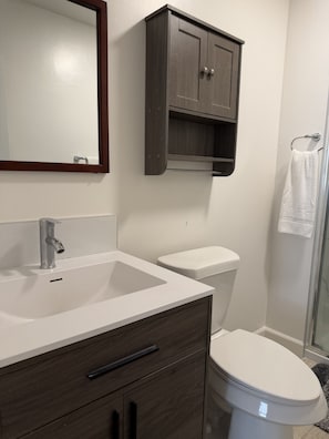 A bathroom with a white sink, dark wooden cabinet, and a toilet.