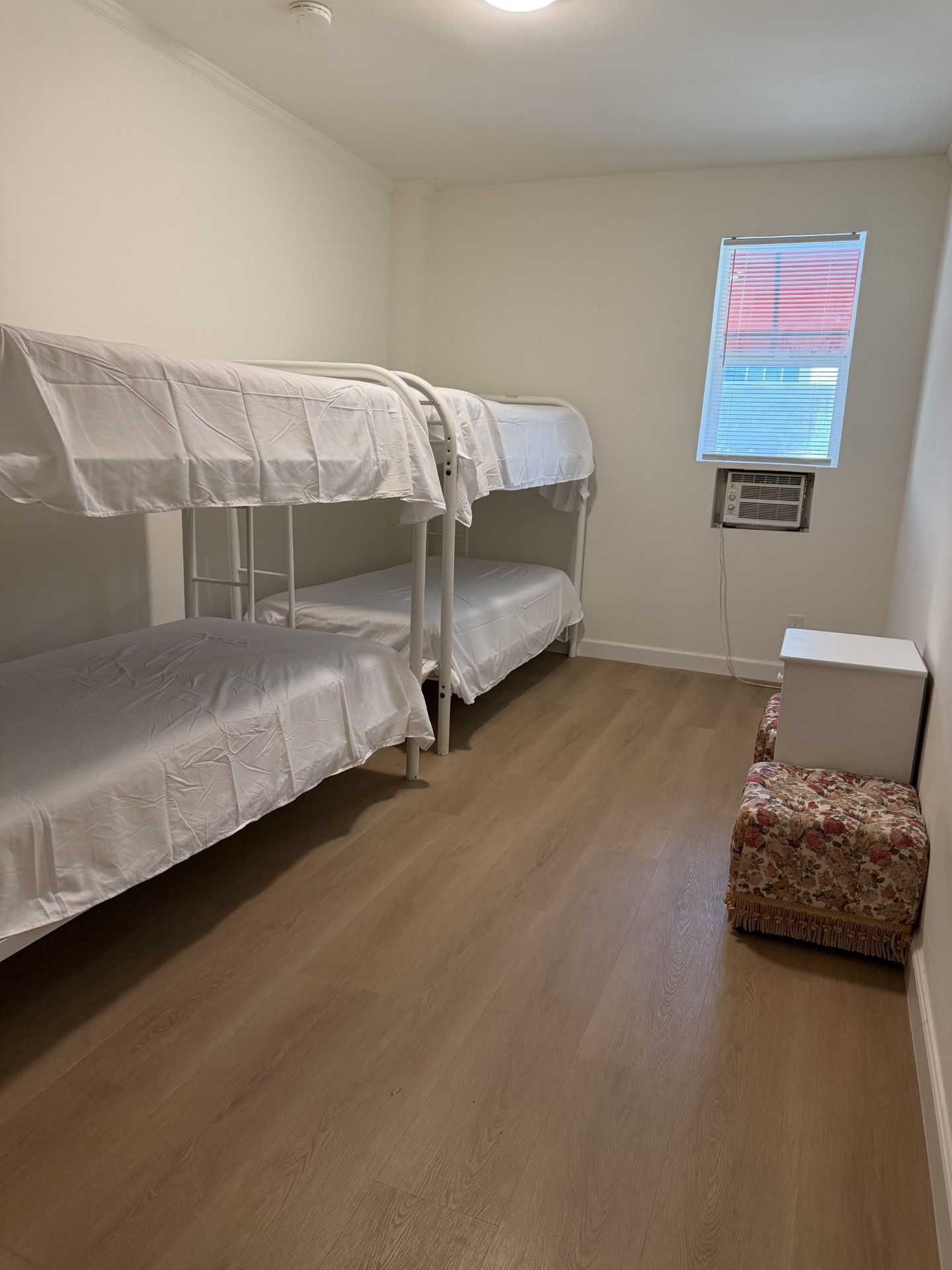 Una habitación con literas, una mesita pequeña y una ventana con persianas.