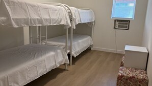 Una habitación con literas, una mesita pequeña y una ventana con persianas.