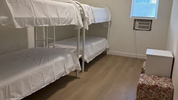 Una habitación con literas, una mesita pequeña y una ventana con persianas.