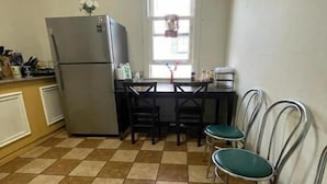 Una cucina con un frigorifero, un tavolo da pranzo con sedie e una finestra.
