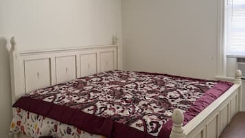 Un dormitorio con cama, banca, ventilador de techo y ventana.
