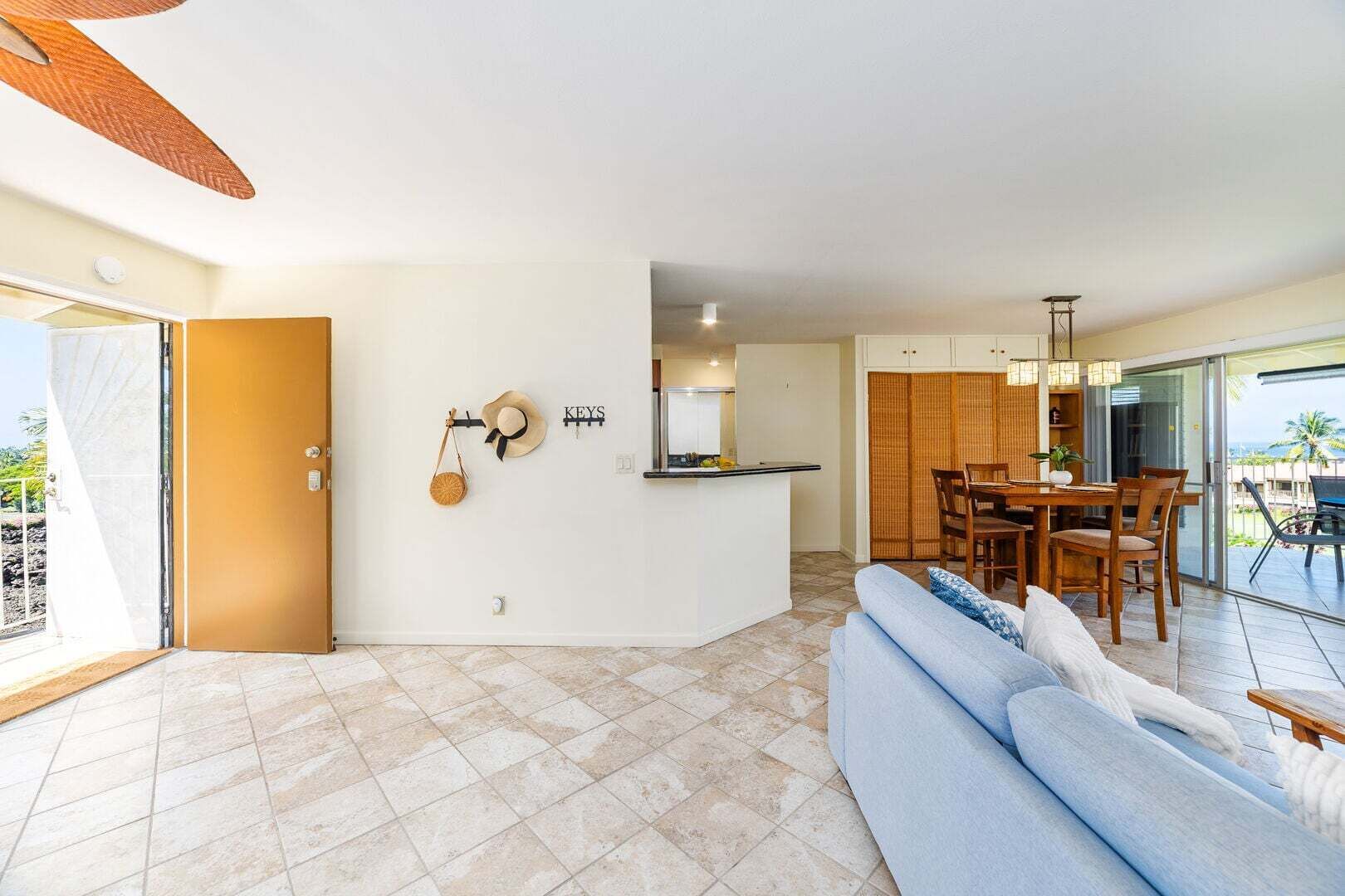 A modern living room with a sofa, dining area, kitchen, and sliding glass doors leading to a balcony.