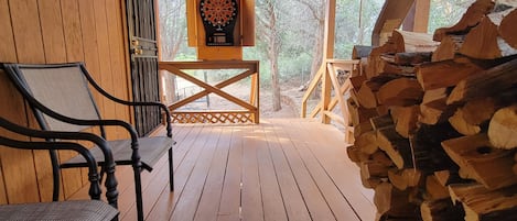 A wooden deck with a dartboard, a chair, and a stack of firewood.