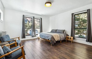 Une chambre à coucher avec un lit, une chaise et de grandes fenêtres.