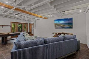 A room with a pool table, a striped sofa, and a painting on the wall. - Coastal Beauty - Canal Front, Dock, Pool, Spa, Game Room by Anna Maria Life Vacation Rentals (Anna Maria)