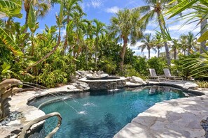 Ein Pool mit Whirlpool, umgeben von Palmen und Felsen.